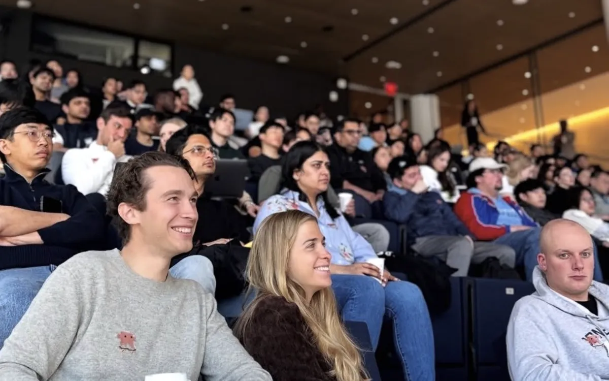 Participants smiling in a full auditorium.