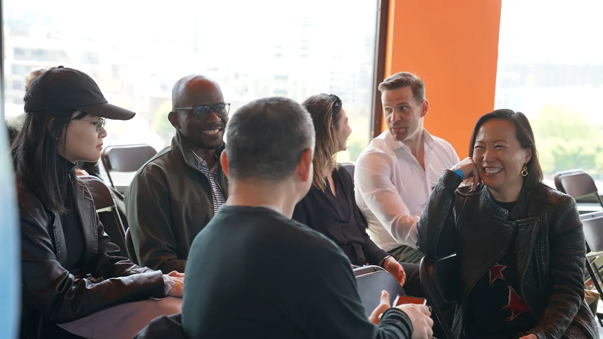 People talking and laughing in a circle of chairs.