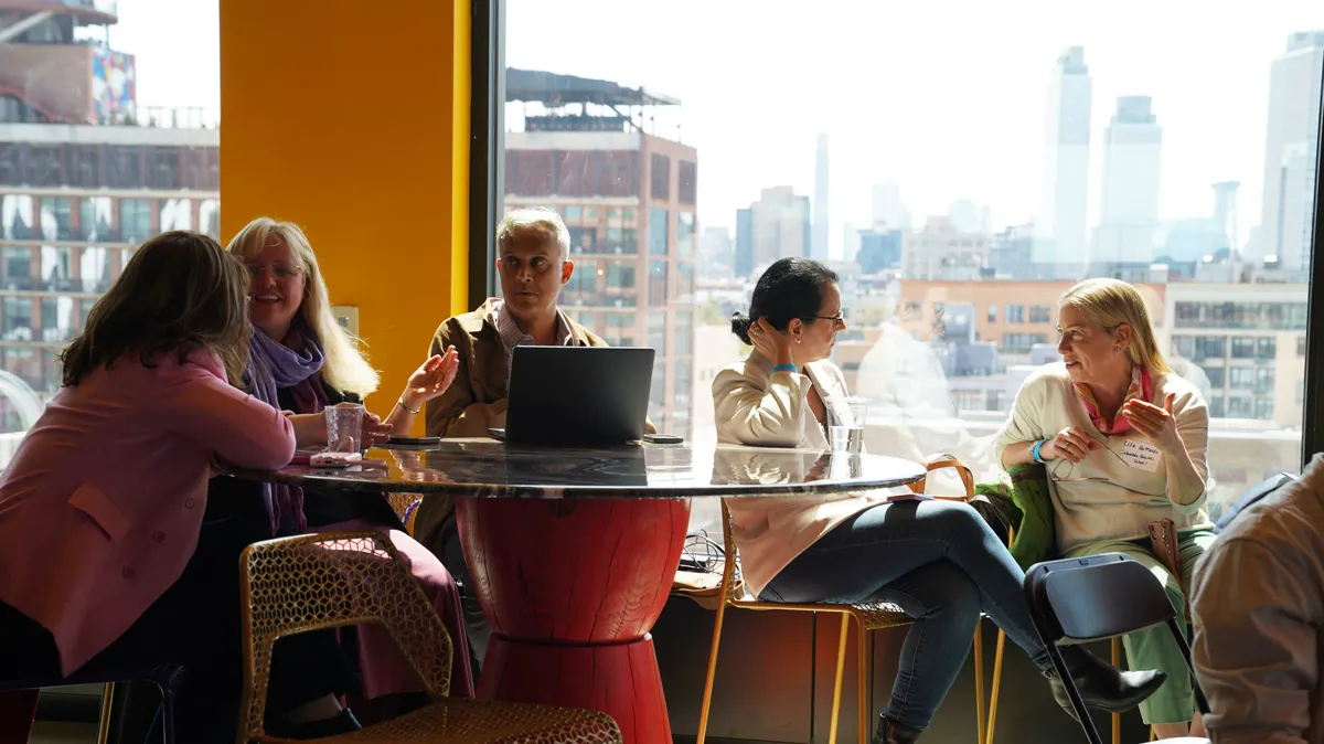 A small group gathered around a table with a laptop.