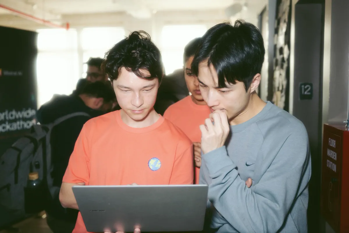 Mistral hackathon participants reviewing a project together around a laptop.
